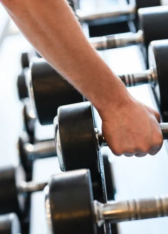 Hand holding weights lined up in the gym 