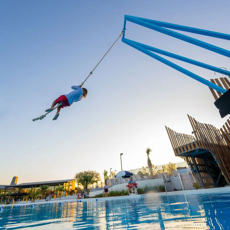 Kid swinging on rope over Blue hole