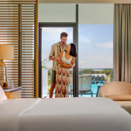 Conrad Orlando Suite An image of a couple in a Conrad Orlando Suite with Evermore Bay in the background at Evermore Orlando Resort.